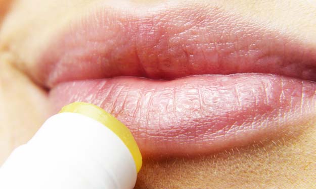 Woman Applying Lip Balm to Dry Chapped Lips.