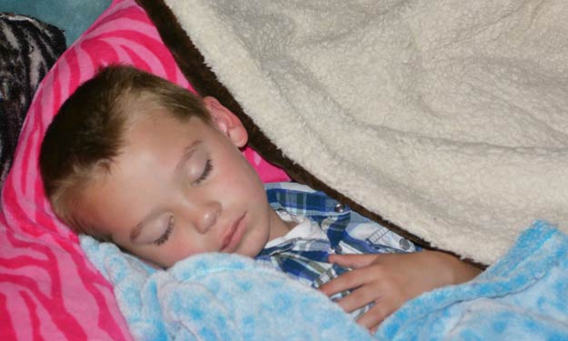 Young Boy with Cold Cuddled Up with Blankets Sleeping.