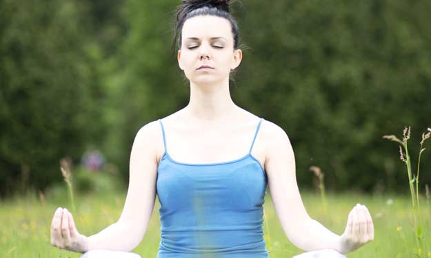 Young Woman Meditating in a Grassy Field.