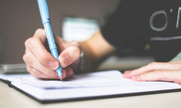 A Man Writing Article in Notebook.